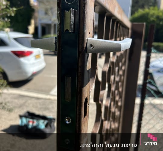 מנעול מותקן על שער מתכת עם תיק כלים ברקע